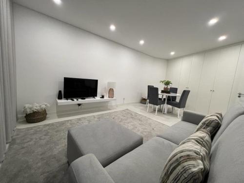 ein Wohnzimmer mit einem Sofa, einem TV und einem Tisch in der Unterkunft Apartamento Prestige Tondela in Tondela