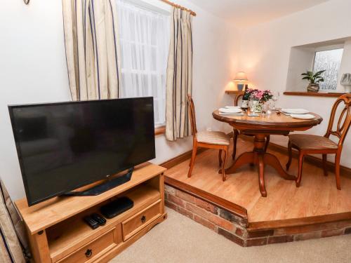 a living room with a flat screen tv and a table at 5A Waterfall Way in Market Harborough