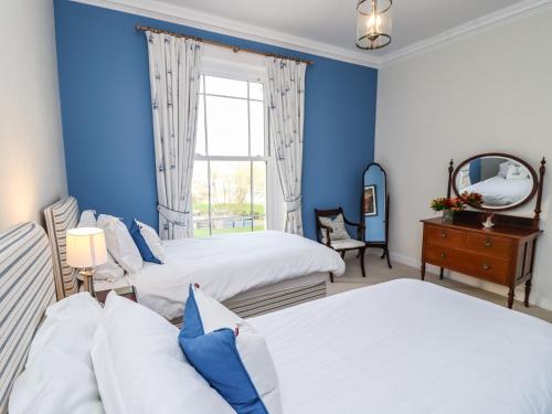 a blue bedroom with two beds and a mirror at Number One The Crescent in Filey