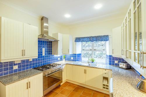 a kitchen with white cabinets and blue tiled walls at Penninghame Mid Lodge in Newton Stewart