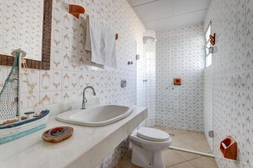 a white bathroom with a sink and a toilet at Praia de Itapirubá in Imbituba
