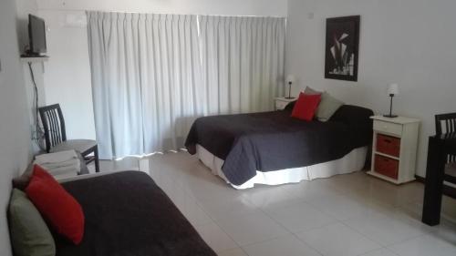 a bedroom with a bed and a couch and a television at Apartamentos Laguna de Navarro in Navarro