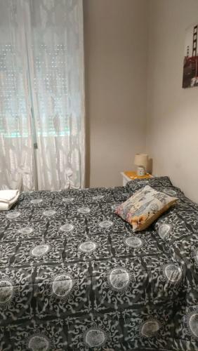 a bed with a black and white blanket and a window at B&B Stadio in Catanzaro
