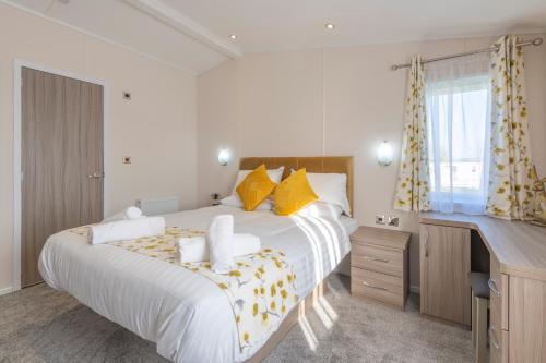 a bedroom with a large white bed with yellow pillows at Marine Holiday Park in Rhyl