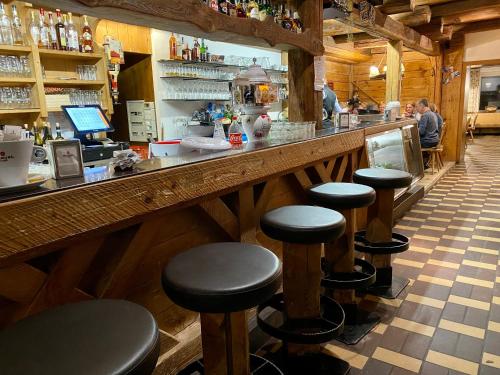 a bar with black stools in a restaurant at Hotel Castel Latemar in Carezza al Lago