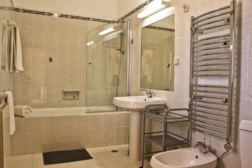 a bathroom with a sink and a tub and a toilet at Villa Santa Barbara by Portucasa in Bordeira