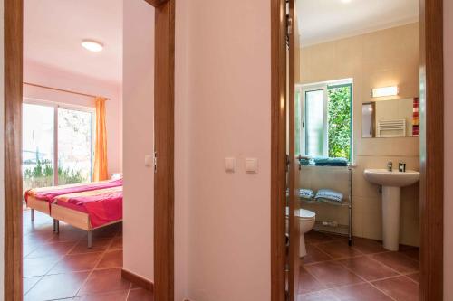 een slaapkamer met een bed en een badkamer met een wastafel bij Casa da Alcaria by Portucasa in Altura