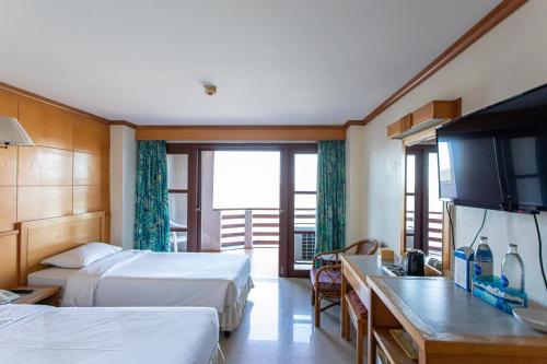 a hotel room with two beds and a flat screen tv at Hadthong Hotel in Prachuap Khiri Khan