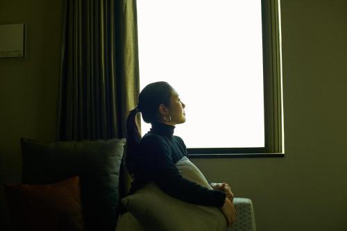 a woman sitting on a couch in front of a window at FAV HOTEL ISE in Ise