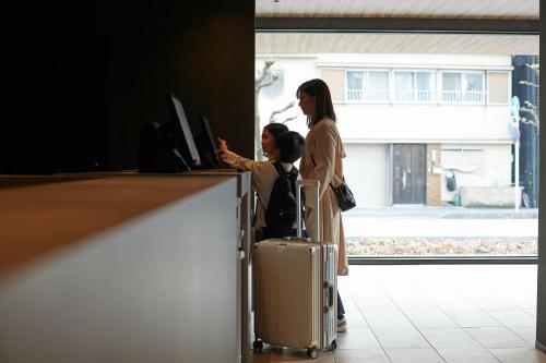 a woman and a man with a suitcase looking at a computer at fav ISE in Ise