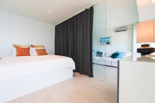 a bedroom with a white bed and a mirror at Turquoise Turtle Apartment - with seaview and A/C in Sesimbra