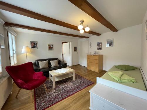 salon z kanapą i czerwonym krzesłem w obiekcie Apartment mit Terrasse No3 w mieście Quedlinburg