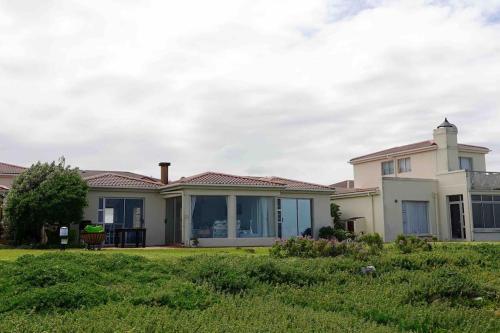 a large white house with a grass yard at Whales & Waves in Hermanus