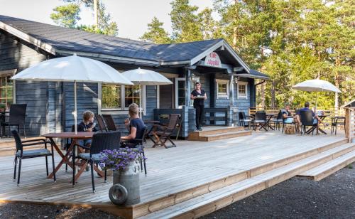 una terraza de madera con gente sentada en una mesa en Cafe Alppila, en Iniö