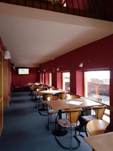 a row of tables and chairs in a room with red walls at Hotel Gold in Terchová