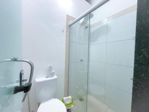 a bathroom with a toilet and a glass shower at Suíte aconchegante no Centro de Caratinga - kitnet in Caratinga