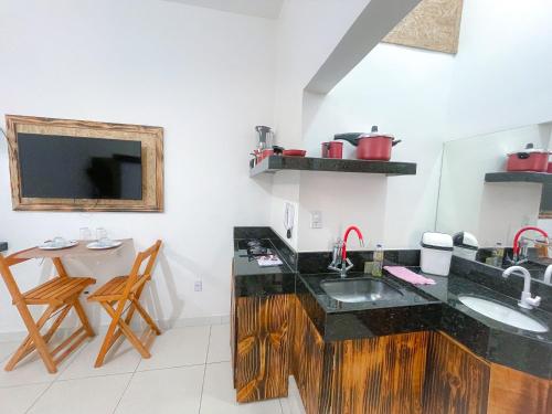 a kitchen with a sink and a table and a tv at Suíte aconchegante no Centro de Caratinga - kitnet in Caratinga