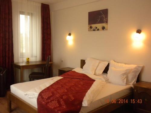 a bedroom with a bed with white sheets and pillows at Pensiunea Cetatea Craiului in Râşnov