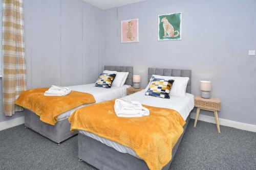 a bedroom with two beds with orange blankets at The Yellow Door by Avenew Management Serviced Accommodation in Stoke on Trent