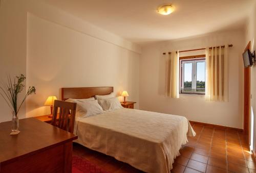 una camera da letto con un letto, una scrivania e una finestra di O Monte da Estrada a Zambujeira do Mar