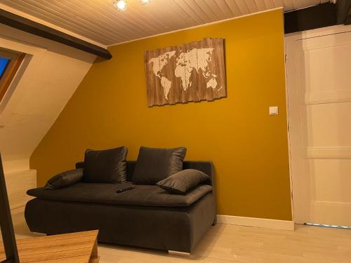 a living room with a couch against a yellow wall at Le petit paradis in Outreau