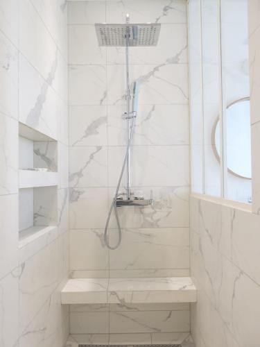 une salle de bain blanche avec une douche avec une porte vitrée dans l'établissement Sacré Coeur CityCosy, à Paris