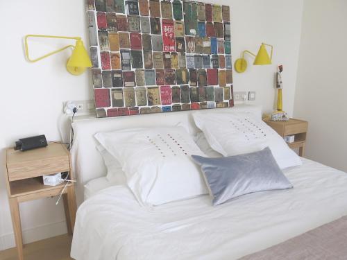 - un lit blanc avec deux oreillers et un mur avec des photos dans l'établissement Sacré Coeur CityCosy, à Paris