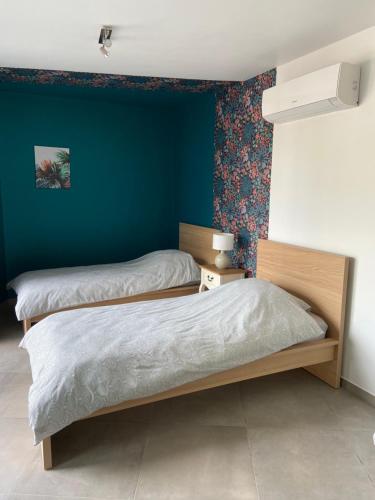 a bedroom with two beds and a blue wall at Gîte de la Chapelle in Samart