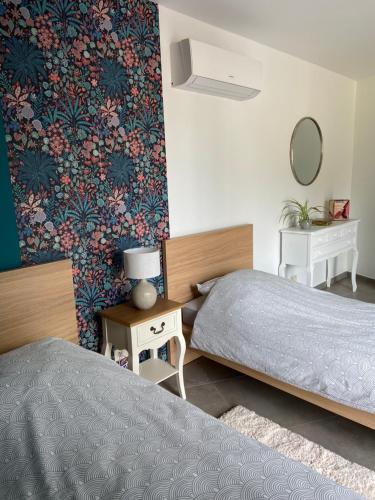 a bedroom with two beds and a wall with floral wallpaper at Gîte de la Chapelle in Samart