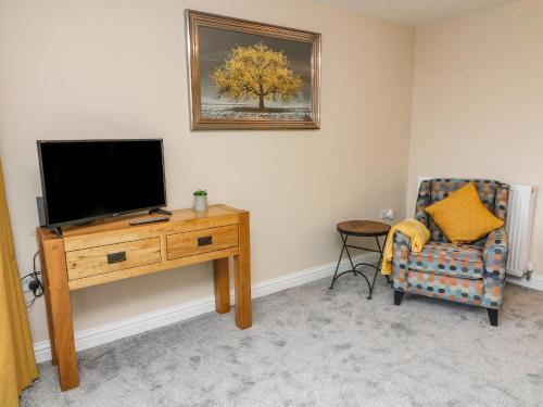 a living room with a television and a chair at Market Lounge in Clitheroe