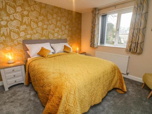 um quarto com uma cama com uma colcha amarela e uma janela em Market Lounge em Clitheroe