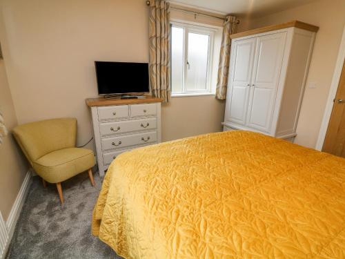 a bedroom with a bed and a chair and a television at Market Lounge in Clitheroe