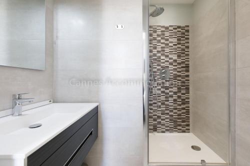 La salle de bains est pourvue d'une douche et d'un lavabo blanc. dans l'établissement Clic 21, à Cannes