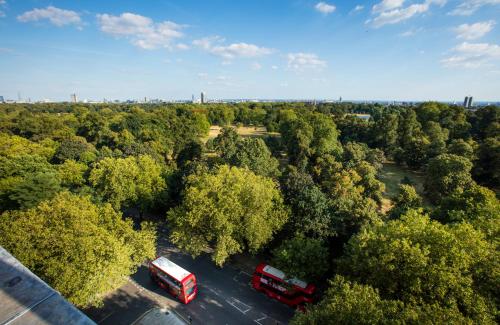 two buses parked in a parking lot with trees at Thistle London Hyde Park Kensington Gardens in London