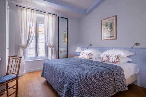 a bedroom with a bed and a window and a chair at La Baronnie Villa & Spa in Saint-Martin-de-Ré