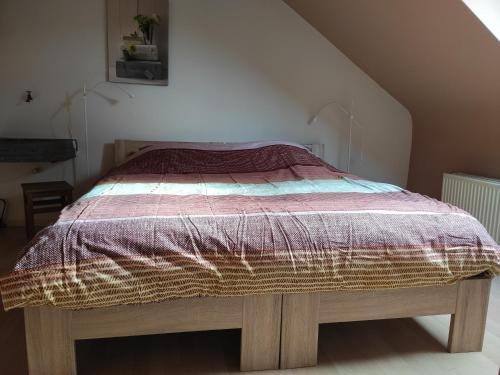 a bedroom with a bed with a purple comforter at Le Héron in Houffalize