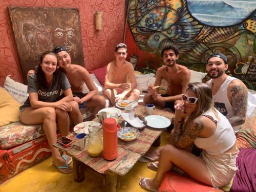 a group of people sitting around a table in a room at Mais Que Nada Itacaré - Hostel, Bar & Breakfast in Itacaré