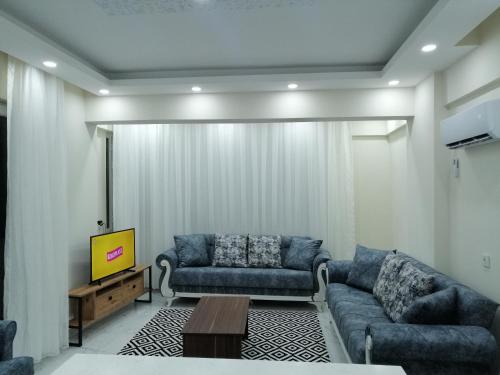 Deniz Apart في دمرة: غرفة معيشة مع اثنين من الأرائك الزرقاء وتلفزيون