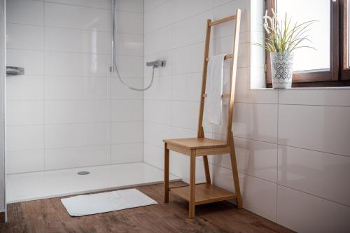 a bathroom with a shower and a wooden chair at M-House FLACHAU Ganzes Haus für 8 Personen in Flachau