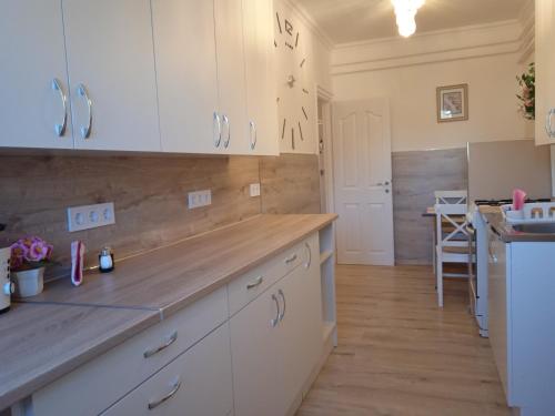 a kitchen with white cabinets and a wooden floor at Fonyódi Centrum Apartman in Fonyód