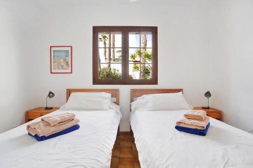 two beds in a room with white walls and a window at Puerto Chico R in Playa Blanca