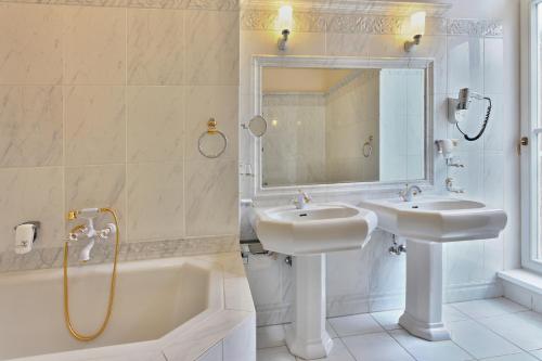 a bathroom with two sinks and a tub and a mirror at Hotel Radium Palace in Jáchymov