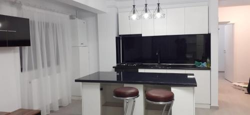 a kitchen with a black counter with two stools at Sweet Home in Iaşi