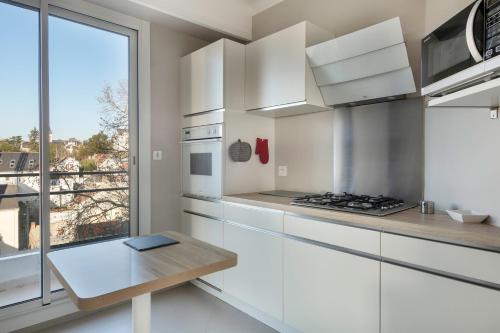 une cuisine blanche avec une table et une fenêtre dans l'établissement Appartement avec vue sur l'Erdre pour 4 personnes, à Nantes