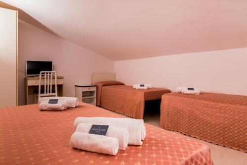 a room with three beds with orange sheets and a tv at Hotel Lydia in Cervia