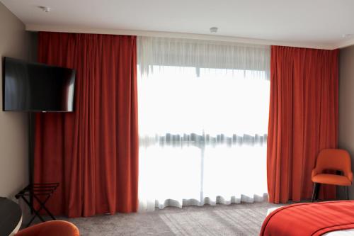 a bedroom with red curtains and a large window at Best Western Plus Le Fairway Hotel & Spa Golf d'Arras in Anzin-Saint-Aubin