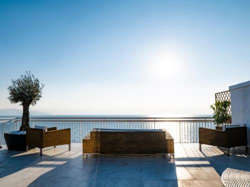 un patio con 2 bancos y un árbol en el balcón en THOMAS SEA VIEW, en Torre del Greco