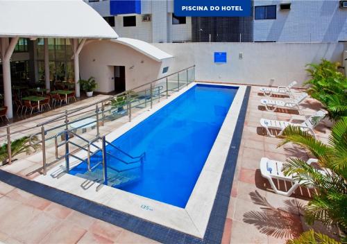 a large swimming pool with chairs and a table at Praiamar Express Hotel in Natal