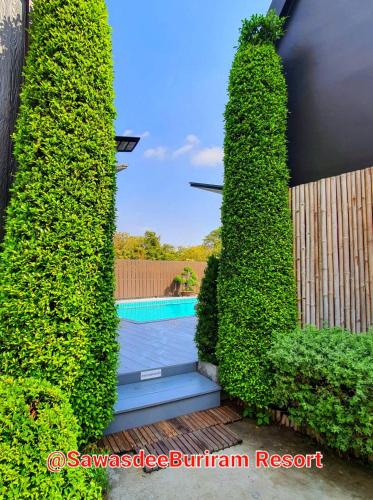 a view of a swimming pool through a hedge at Sawasdee​ Buriram​ Resort in Buriram