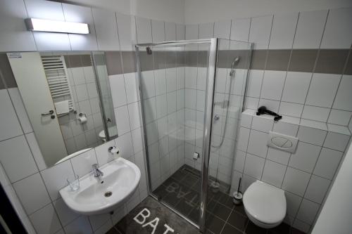 uma casa de banho com um chuveiro, um lavatório e um WC. em Sport Centrum Apartman em Pápa